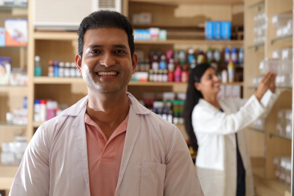 Pharmacist chemist Indian man standing in pharmacy - drugstore. Close up of pharmacist at the hospital pharmacy. Pharmacist assisting to customers in pharmacy.